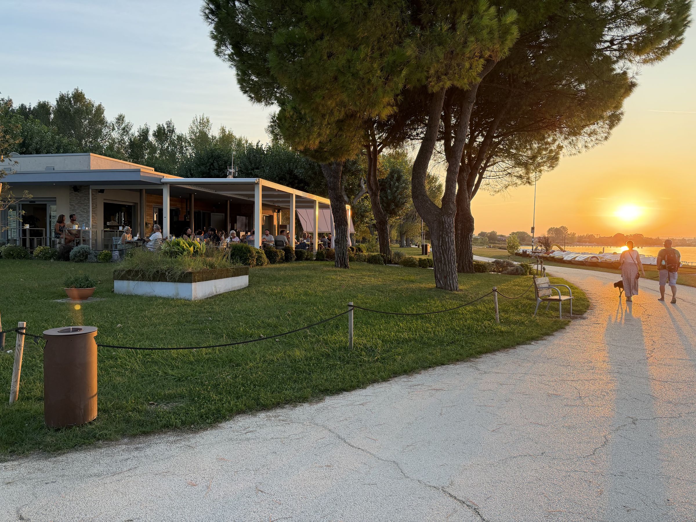 Il Punta Grò Bistrot e il giardino con il sole che tramonta tra i pini sul lago